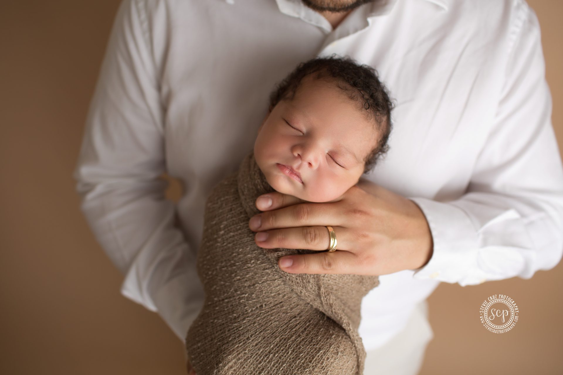 newborn baby all cozy with father for a picture during his newborn photoshoot