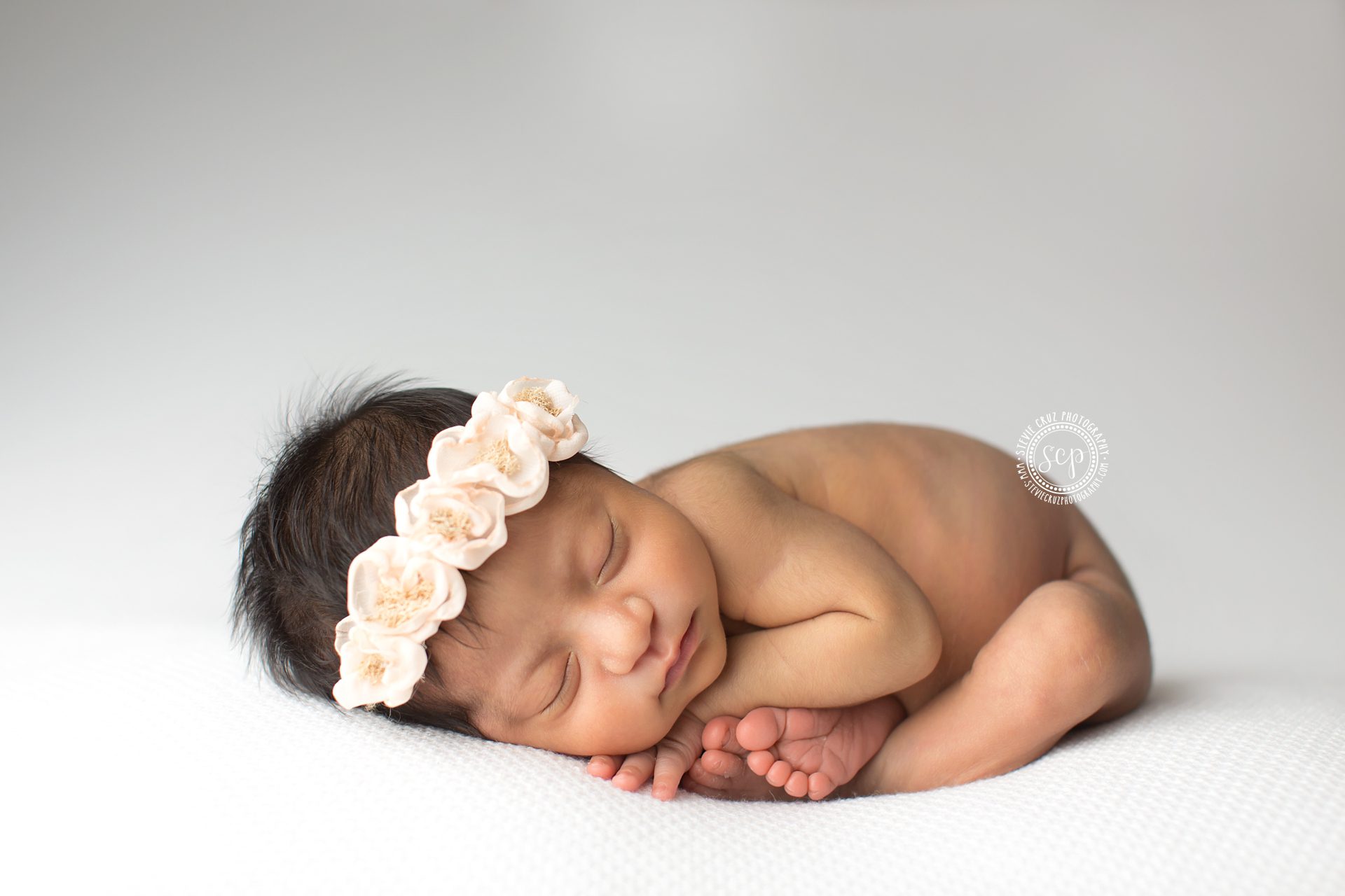 Professional newborn baby photographer in Orange County captures this precious baby girl. Love her floral head band